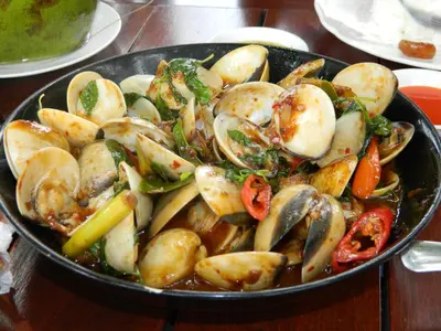 a pan of food with mushrooms and vegetables on a table at Sugar and Spice Inn in Kata Beach