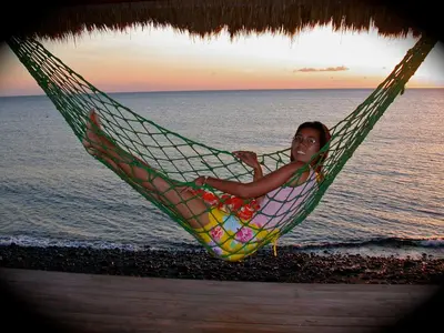 a woman laying in a hammock on the beach at Sugar and Spice Inn in Kata Beach