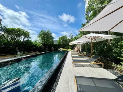 a swimming pool with chairs and umbrellas next to a building at New apartment 2bedrooms in Laguna lakeside Bang Tao beach in Phuket