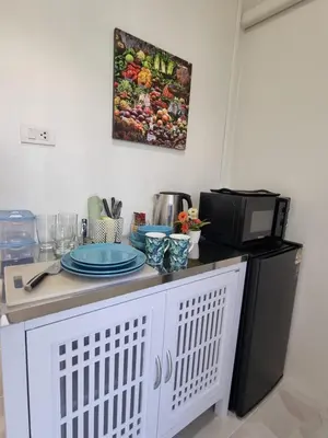 a kitchen with a microwave and a table with plates on it at Songbird Suites in Ban Khlong Haeng