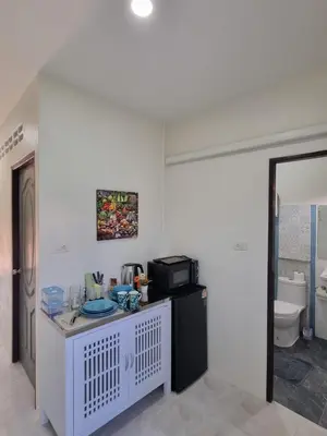 a white kitchen with a counter with a microwave at Songbird Suites in Ban Khlong Haeng