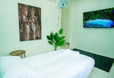 a bedroom with a large white bed and a plant at Songbird Suites in Ban Khlong Haeng
