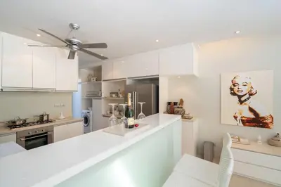 a kitchen with white cabinets and a ceiling fan at Sea view Villa on Rawai beach in Ban Saiyuan (1)