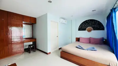 a bedroom with a bed with pink pillows and a desk at Lucky One Guesthouse in Patong Beach