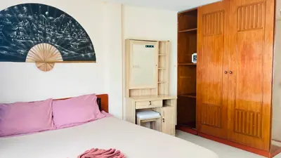 a bedroom with a bed and a wooden cabinet at Lucky One Guesthouse in Patong Beach