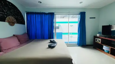 a bedroom with a large bed with blue curtains at Lucky One Guesthouse in Patong Beach