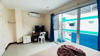 a room with a bed and a desk and a window at Lucky One Guesthouse in Patong Beach
