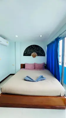 a bedroom with a large bed with blue curtains at Lucky One Guesthouse in Patong Beach