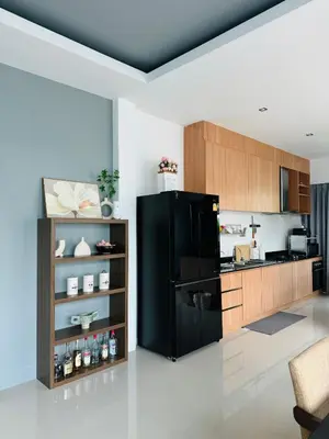 a kitchen with a black refrigerator and wooden cabinets at Funtime pool villa in Kata Beach