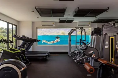 a gym with two treadmills and a woman in the water at Duplex Condo pool access in Rawai Beach