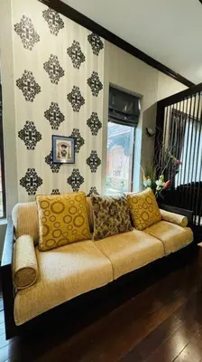 a couch with pillows sitting in a living room at Vela House Phuket in Changwat Phuket