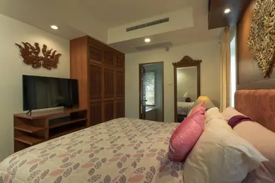 a bedroom with a bed with pink pillows and a television at Villa on Panwa with 2 house keepers in Ban Bo Rae