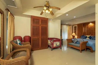a bedroom with a bed and chairs and a ceiling fan at Villa on Panwa with 2 house keepers in Ban Bo Rae