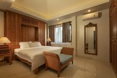 a bedroom with a bed and a chair and a mirror at Villa on Panwa with 2 house keepers in Ban Bo Rae