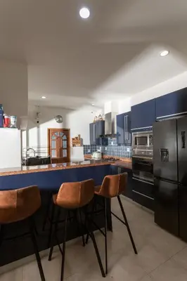 a kitchen with blue cabinets and a counter with stools at Villa on Panwa with 2 house keepers in Ban Bo Rae