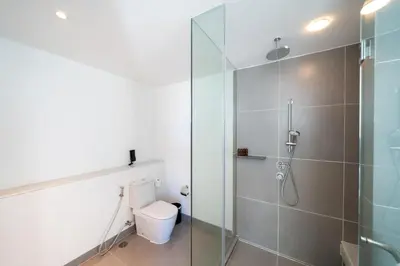 a bathroom with a toilet and a glass shower at Karon Seaview Beachfront - 2 BR Apartment At Paradox Residence in Karon Beach