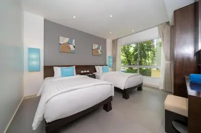 a bedroom with two beds and a desk and a window at Karon Seaview Beachfront - 2 BR Apartment At Paradox Residence in Karon Beach