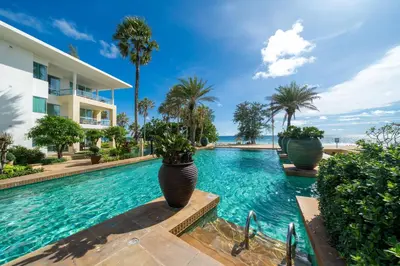 a swimming pool with palm trees and a building at Karon Seaview Beachfront - 2 BR Apartment At Paradox Residence in Karon Beach