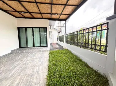a hallway of a building with green grass at Mali Villa in Ban Suan