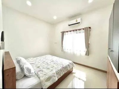 a white bedroom with a bed and a window at Mali Villa in Ban Suan