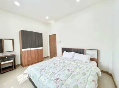 a bedroom with a large bed and a sink at Mali Villa in Ban Suan