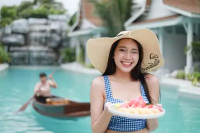 a woman in a hat holding a plate of food at Lalynn Resort & Villas, Phuket in Thalang