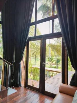 a room with a large glass door with curtains at Cheewatra Farmstay Phuket ชีวาตรา ฟาร์มสเตย์ ภูเก็ต in Thalang