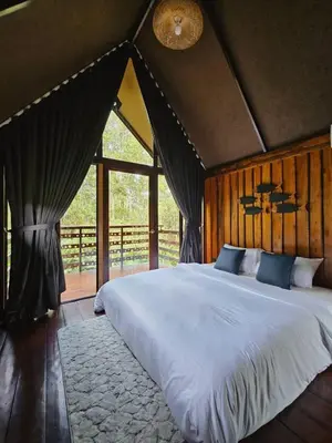 a bedroom with a large bed with a large window at Cheewatra Farmstay Phuket ชีวาตรา ฟาร์มสเตย์ ภูเก็ต in Thalang
