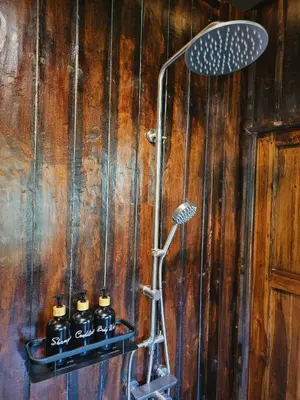 a shower in a bathroom with wooden walls at Cheewatra Farmstay Phuket ชีวาตรา ฟาร์มสเตย์ ภูเก็ต in Thalang