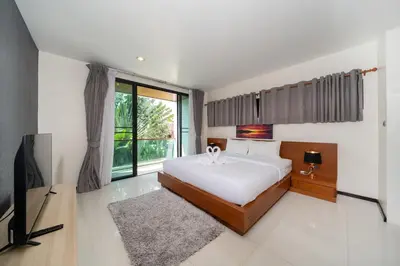 a bedroom with a large bed and a television at The fin villa rawai 2 bedroom in Ban Saiyuan (1)