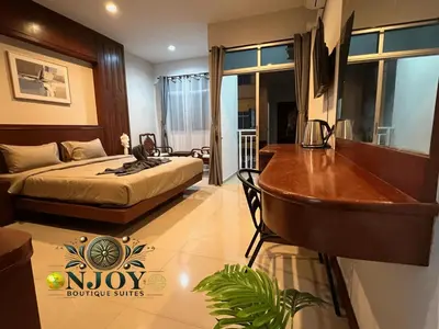 a bedroom with a bed and a desk and a tub at NJoy Boutique Guesthouse in Patong Beach