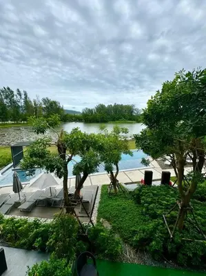 a view of a body of water with chairs and trees at 2bedrooms Cassia Residence lake view in Phuket