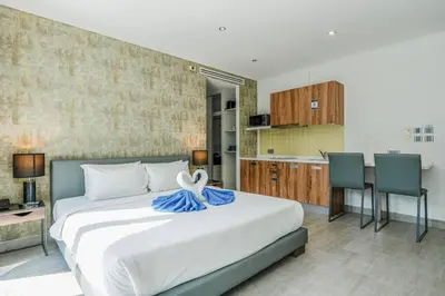 a bedroom with a large white bed and a kitchen at Minuets 2 Patong Beach Twin Sand Resort & Spa! C152 in Patong Beach