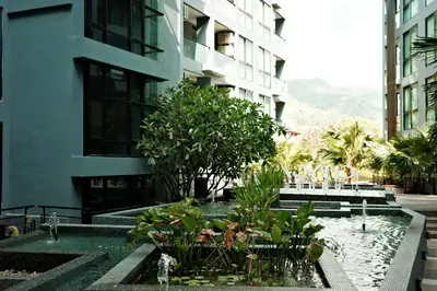 a courtyard in a building with a fountain and trees at City Gate Kamala N103 by Phuket Sabay Rent in Kamala Beach