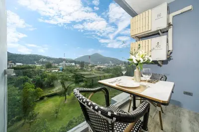 a balcony with a table and chairs and a view at Citygate Kamala Resort in Kamala Beach
