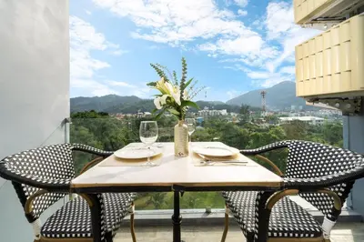 a table with chairs and a vase of flowers on a balcony at Citygate Kamala Resort in Kamala Beach