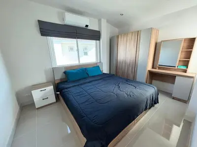 a bedroom with a bed with blue pillows and a window at Cozy House by Cody One in Thalang