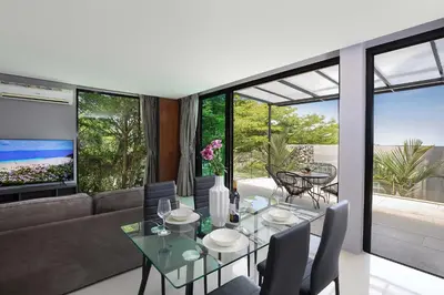 a living room with a glass table and chairs at Sea View & Tropical Bliss - 2BR Villa Natural Touch A4 at Kamala Hill in Kamala Beach