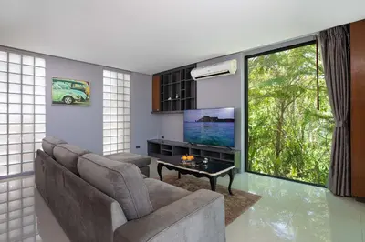 a living room with a couch and a flat screen tv at Sea View & Tropical Bliss - 2BR Villa Natural Touch A4 at Kamala Hill in Kamala Beach