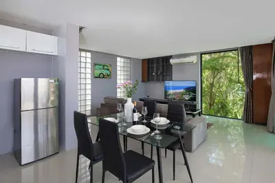a kitchen and dining room with a table and a television at Sea View & Tropical Bliss - 2BR Villa Natural Touch A4 at Kamala Hill in Kamala Beach