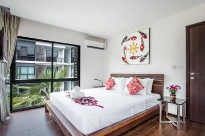 a bedroom with a bed with white sheets and red pillows at Tropical Pool View 1BR Apartment TTL F303 in Rawai Beach Residence in Rawai Beach