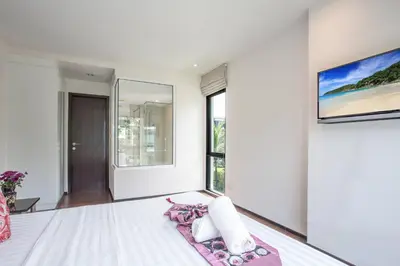a white bedroom with a large bed and large windows at Tropical Pool View 1BR Apartment TTL F303 in Rawai Beach Residence in Rawai Beach