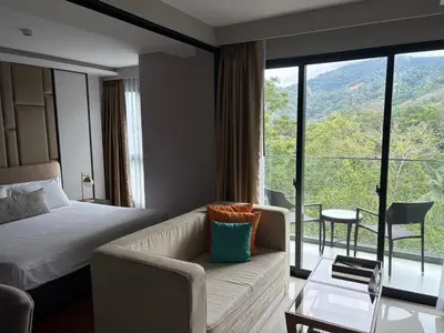 a hotel room with a bed and a couch and a window at Mida 1 in Phuket Town