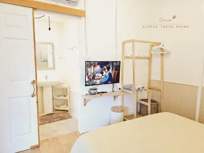 a room with a table and a tv on a wall at Little Latte House - Chalong in Ban Na Bon