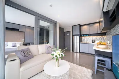 a living room with a white couch and a kitchen at CityGate Kamala in Kamala Beach