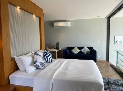 a bedroom with a large white bed and a blue couch at Seaview 2 BR Spacious Modern Duplex near Kamala beach in Kamala Beach