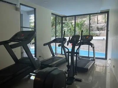 a gym with three cardio machines and a window at Seaview 2 BR Spacious Modern Duplex near Kamala beach in Kamala Beach