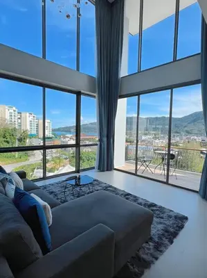a living room with a couch and large windows at Seaview 2 BR Spacious Modern Duplex near Kamala beach in Kamala Beach