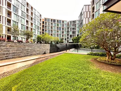 a green lawn in front of some buildings at the base updown\u4e00\u5367 in Phuket Town
