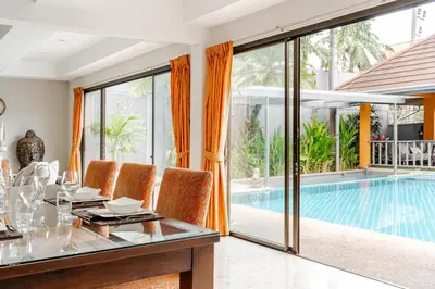 a dining room with a table and a swimming pool at Luxury 4BR Villa with Pool & Ocean Views on Patong in Patong Beach